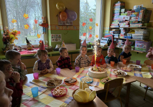 Dzieci siedzą przy stolikach podczas poczęstunku.