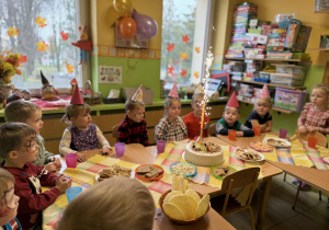 Dzieci siedzą przy stolikach podczas poczęstunku.
