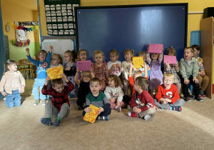 Dzieci siedzą i pokazują prezenty.