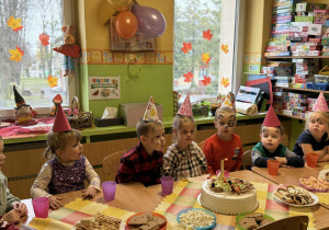 Dzieci siedzą przy stolikach podczas poczęstunku.