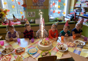 Dzieci siedzą przy stolikach podczas poczęstunku.