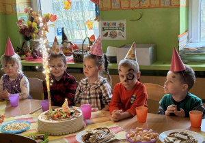 Dzieci siedzą przy stolikach podczas poczęstunku.