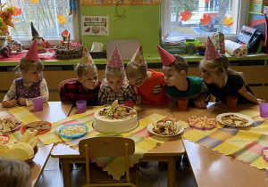 Dzieci siedzą przy stolikach podczas poczęstunku.