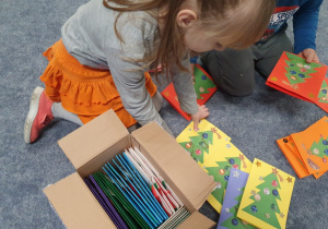 Dziewczynka pakuje przygotowane przez przedszkolaki kartki.