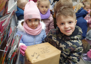 Dzieci na poczcie wysyłają paczkę ze świątecznymi kartkami.