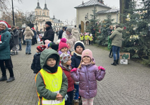 Dzieci w parku ubierają świąteczne drzewko.