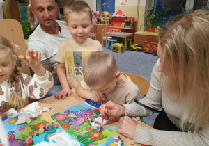 Dzieci malują ozdoby wspólnie z rodzicami.