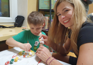 Dzieci malują ozdoby wspólnie z rodzicami.