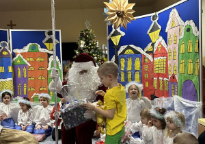 Mikołaj rozdaje dzieciom prezenty.