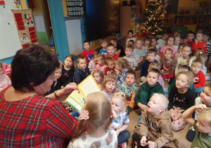 Dzieci słuchają opowiadania czytanego przez emerytowanego pracownika przedszkola.