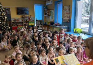 Dzieci słuchają opowiadania czytanego przez emerytowanego pracownika przedszkola.