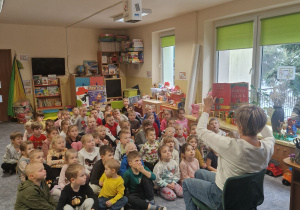 Dzieci słuchają opowiadania czytanego przez emerytowanego pracownika przedszkola.
