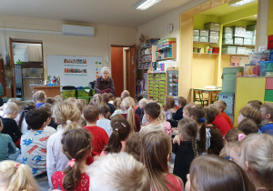 Dzieci słuchają opowiadania czytanego przez emerytowanego pracownika przedszkola.