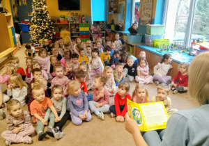 Dzieci słuchają opowiadania czytanego przez emerytowanego pracownika przedszkola.