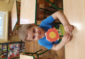 Chłopiec trzyma wycięty z papieru kwiatek.