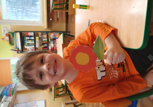 Chłopiec trzyma wycięty z papieru kwiatek.