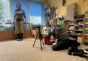 Dzieci słuchają i oglądają sprzęt fotograficzny.