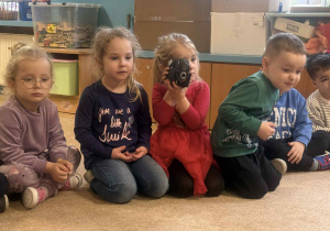 Dzieci słuchają i oglądają sprzęt fotograficzny.