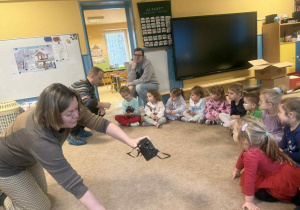 Dzieci słuchają i oglądają sprzęt fotograficzny.