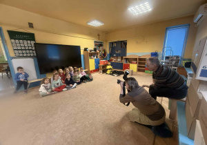 Dzieci słuchają i oglądają sprzęt fotograficzny.