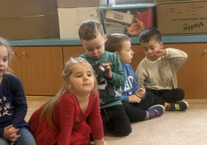 Dzieci słuchają i oglądają sprzęt fotograficzny.