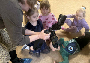 Dzieci słuchają i oglądają sprzęt fotograficzny.