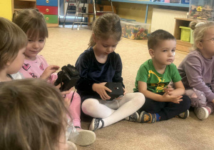 Dzieci słuchają i oglądają sprzęt fotograficzny.