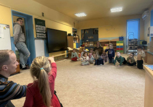 Dzieci słuchają i oglądają sprzęt fotograficzny.