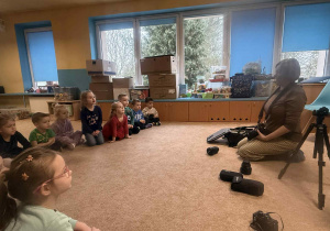 Dzieci słuchają i oglądają sprzęt fotograficzny.