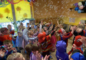 Dzieci łapią bańki mydlane.