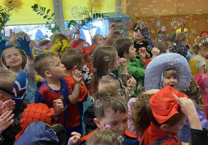 Dzieci łapią bańki mydlane.