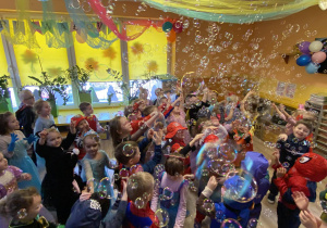 Dzieci łapią bańki mydlane.