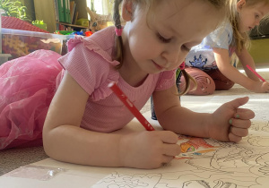 dziewczynka koloruja pracę plastyczną