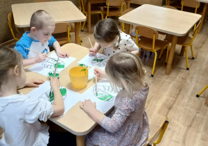 dzieci malują farbami kontur liścia monstery