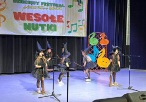 Dzieci prezentują na scenie układ taneczny.