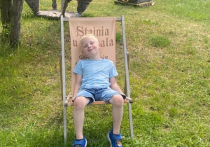 Chłopiec siedzi na leżaku