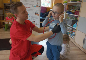 Dziecko słucha bicia serca za pomocą stetoskopu.
