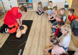 Ratownik prezentuje sposób uciskania klatki piersiowej.