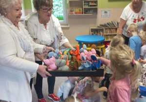 Seniorki wręczają dzieciom upominki.