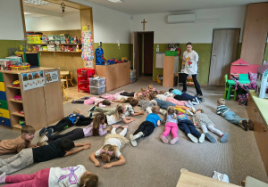 Dzieci leżą na dywanie wykonują polecenia instruktorki.
