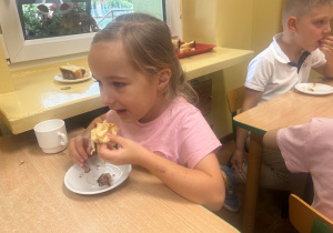 Dziecko zjada przygotowane na zajęciach ciasto drożdżowe.