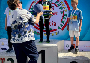 Chłopiec odbiera medal i maskotkę.