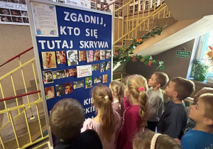 Dzieci oglądają zdjęcia pracowników przedszkola z okresu dzieciństwa.