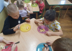 Dzieci jedzą przygotowaną sałatkę jarzynową.