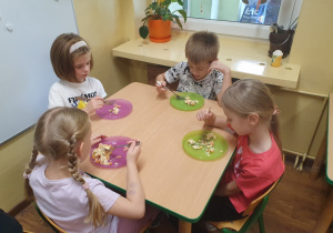 Dzieci jedzą przygotowaną sałatkę jarzynową.