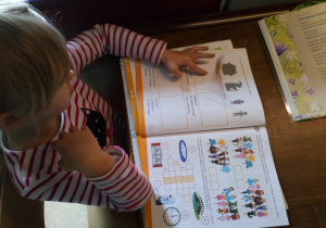 Eliza rozwiązuje zadania z kart pracy