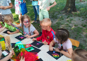 Dzieci przy stoliku tworzą magiczne obrazki za pomocą wykałaczki.
