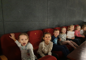 Dzieci siedzą na fotelach i oglądają film.