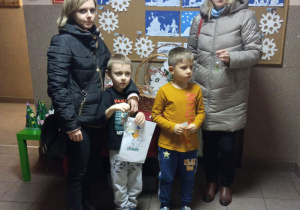 Dzieci wraz z rodzicami z zakupionymi na kiermaszu ozdobami.