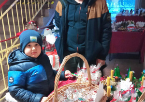 Rodzic z dziećmi wybierają ozdoby na świątecznym kiermaszu.